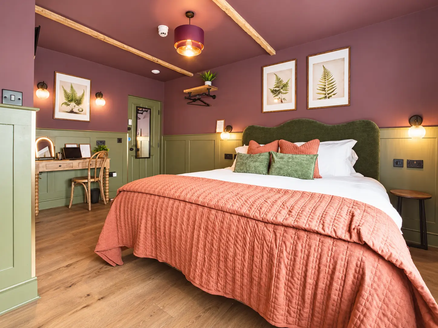 Room 1 at The Linen Rooms with a green velvet headboard, terracotta quilt and botanical prints
