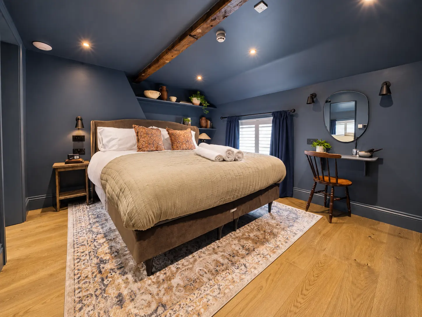A navy bedroom at The Silk Rooms with a super king bed and exposed timber beam